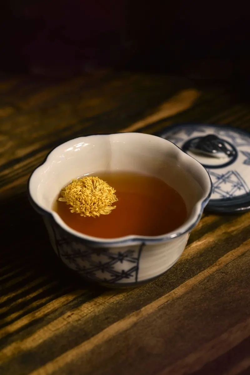 青花瓷碗裡泡著一朵菊花的茶湯
