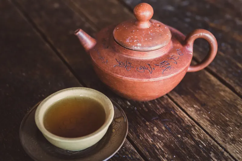 木桌上的陶壺與一杯剛倒好的熱茶